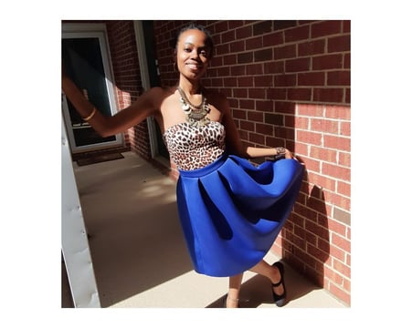 Angela posing with long blue skirt, leopard print tube top, and gold jewelry